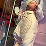 newborn, baby, sleeping, hospital, bassinet, pink_onesie, knitted_cap, infant, soft_lighting, blanket, cute, peaceful, person, bed, fabric, rest, small_hands, indoor, cozy, portrait