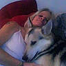 Aspen Waya joined the competition — help win amazing prizes! person, dog, couch, red_cushion, indoor, blurry, dim_light, white_tank_top, tattoo, pet, hugging, close_up, animal, furniture, relaxing, companion, domestic, canine, friendship, casual