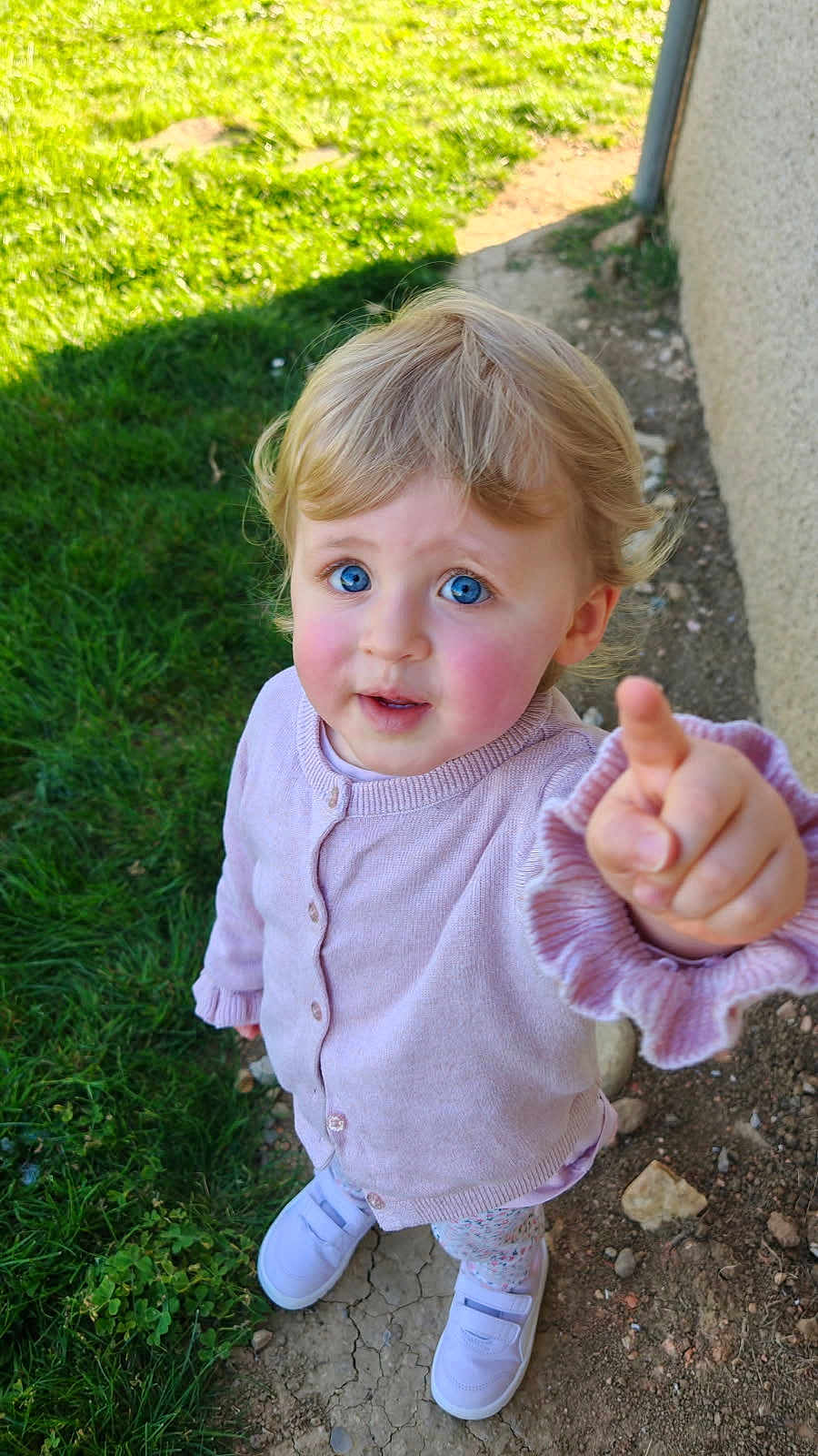 Sélène a rejoint le concours — aidez-le/la à gagner de superbes lots ! toddler, child, pointing, outdoor, grass, dirt, blue_eyes, pink_cardigan, shoes, curly_hair, rosy_cheeks, daylight, casual_clothing, person, young_child, standing, nature, exploration, cute, curiosity