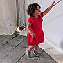 Nour-Elsa a rejoint le concours — aidez-le/la à gagner de superbes lots ! toddler, child, red_dress, curly_hair, reaching, rope, tent, stone_floor, footwear, pink_socks, outdoor, side_view, standing, young_child, casual, playful, expression, person, clothing, daylight