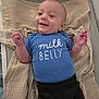 Titan is registered to the contest to win money with this photo: baby, infant, blue_onesie, milk_belly_text, blanket, smiling, happy, lying_down, clothing, cute, child, indoor, puma_pants, small_hands, face, head, skin, eyes, mouth, newborn