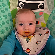 Kaylen joined the competition — help win amazing prizes! baby, infant, bib, messy, food_stains, highchair, baby_seat, curious, blue_clothing, hot_air_balloon_pattern, face, hands, indoor, child, cute, expression, portrait, colorful, soft_lighting, young