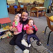 Layla is registered to the contest to win money with this photo: adult, bookshelves, bottle, candid, carpet, child, dollhouse, family, furniture, girl, hugging, indoor, library, man, play, sitting, smile, toddler, toy, toys