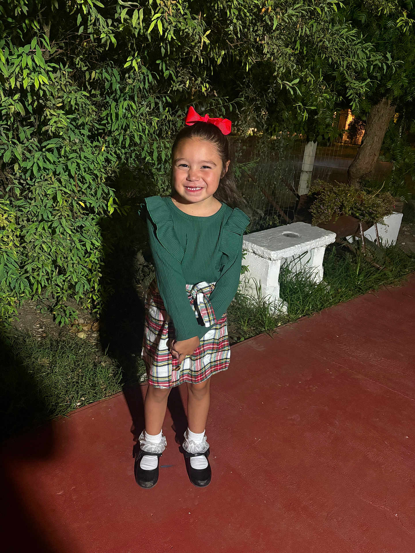 Layla joined the competition — help win amazing prizes! child, girl, smile, red_bow, green_top, plaid_skirt, white_socks, black_shoes, night, outdoor, pavement, bench, greenery, plants, shadow, happy, portrait, fashion, cute, standing