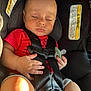 baby, sleeping, car_seat, pacifier, red_shirt, child, infant, seat_belt, safety, resting, cute, hands, clothing, indoors, young_child, peaceful, portrait, car_interior, warning_label, closeup