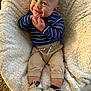 Colton is registered to the contest to win money with this photo: baby, smile, infant, striped_shirt, pants, shoes, blanket, cozy, hands, cute, happy, child, portrait, indoor, soft_texture, sitting, footwear, warm, expression, comfortable