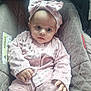 baby, infant, pink_clothing, headband, bow, car_seat, child, cute, indoors, soft_texture, clothing, face, person, hand, expression, seated, portrait, adorable, young_child, cozy