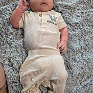 Achilles is registered to the contest to win money with this photo: baby, infant, clothing, blanket, soft_texture, lying_down, cute, portrait, child, cozy, elephant_print, fabric, feet, hands, looking_up, comfortable, casual_wear, indoor, relaxed, person