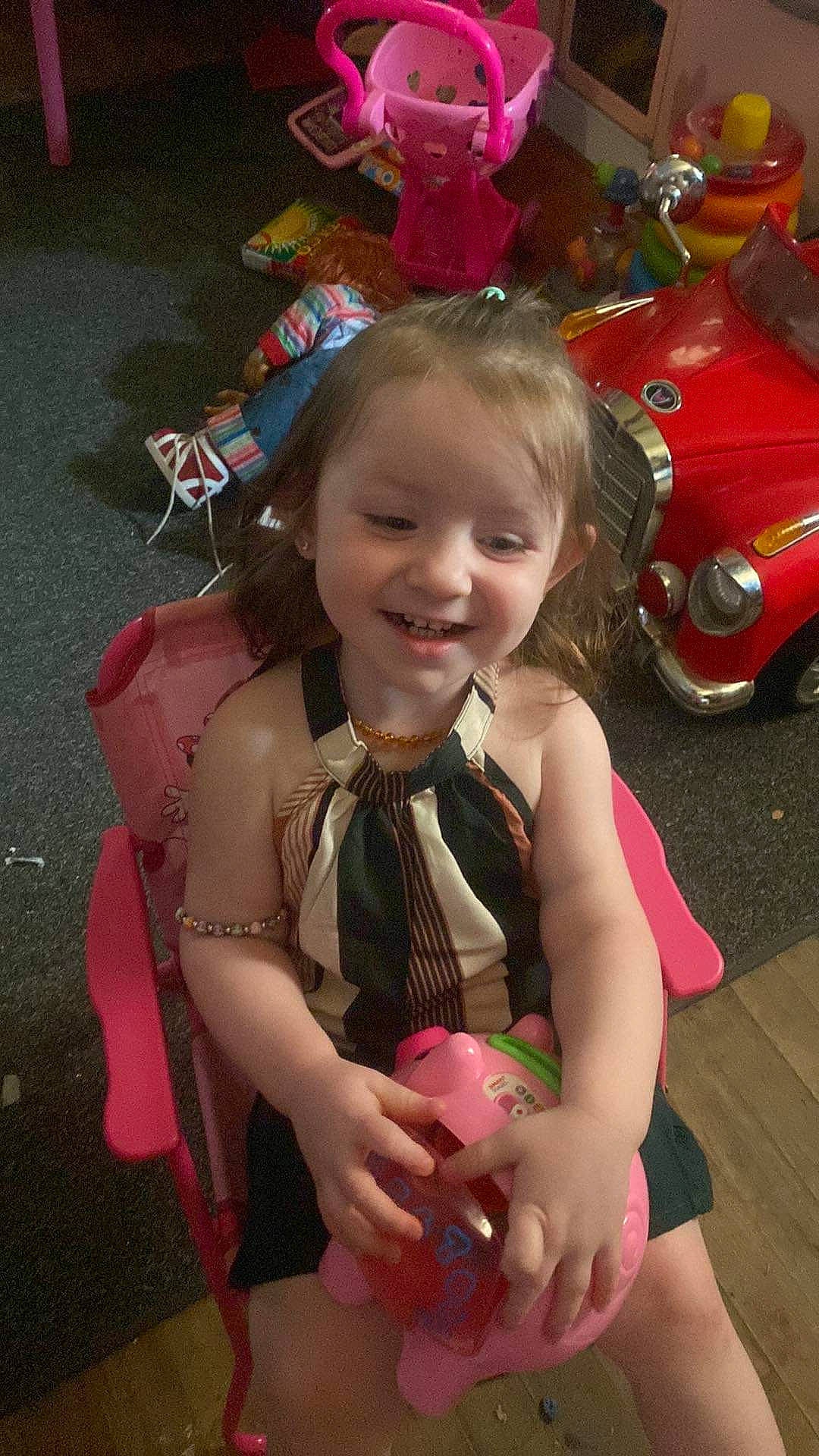 Esme is registered to the contest to win money with this photo: beauty, child, classic_car, event, facial_expression, family_car, fashion_accessory, fictional_character, fun, happy, joy, motor_vehicle, person, photograph, pink, sitting, smile, snapshot, tire, toddler