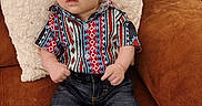 Matteo joined the competition — help win amazing prizes! baby, child, infant, couch, pillow, clothing, shirt, jeans, boots, furniture, indoor, portrait, curious, seated, cute, person, young, patterned_shirt, cozy, brown