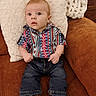 baby, child, infant, couch, pillow, clothing, shirt, jeans, boots, furniture, indoor, portrait, curious, seated, cute, person, young, patterned_shirt, cozy, brown