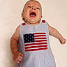 Matteo joined the competition — help win amazing prizes! baby, infant, child, striped_clothing, american_flag, patch, red_buttons, blue_and_white, expression, mouth_open, lying_down, skin, arm, hand, face, head, eyes, nose, background, fabric