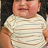 baby, child, smiling, striped_shirt, pillow, indoor, cheeks, shorts, face, cute, infant, resting, hand, comfort, person, young_child, head, skin, portrait, happy