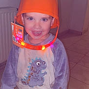 Lyno a rejoint le concours — aidez-le/la à gagner de superbes lots ! child, smiling, pajamas, dinosaur, helmet, orange_helmet, indoor, tile_floor, happy, boy, light, plastic, clothing, home, cute, person, portrait, playful, toy, floor