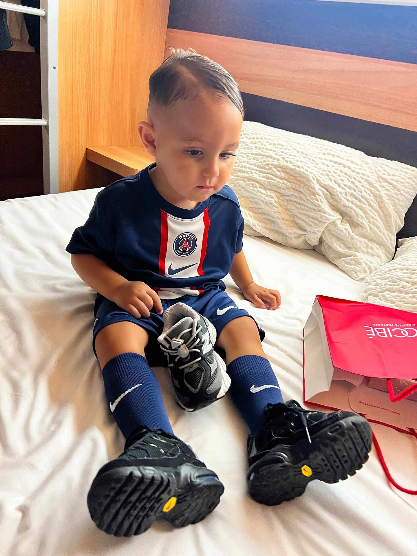 Kais participe au concours pour gagner de l'argent avec cette photo : toddler, child, bed, sneaker, shoes, socks, sportswear, nike, psg, clothing, indoor, pillow, shopping_bag, furniture, person, portrait, cute, serious, hair, floor