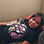 bedroom, blanket, cartoon_graphic, casual, child, comfort, cuddle, cute, gray_and_white_cat, indoor, kitten, lying_down, pillow, portrait, relax, resting, shirt, smile, wall, young_person