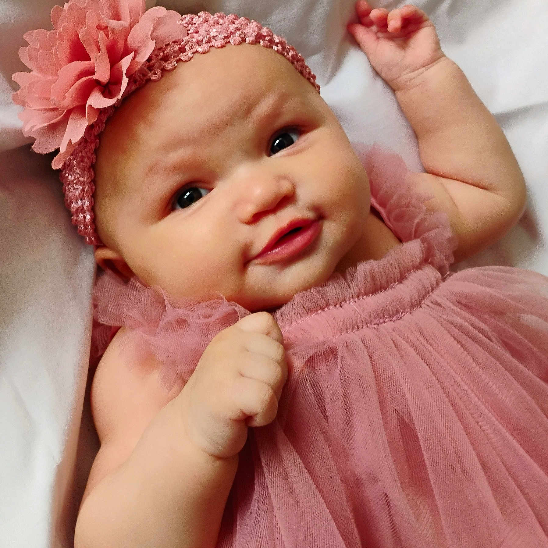 Azira is registered to the contest to win money with this photo: adorable, baby, child, close_up, cute, fabric, face, flower, hand, headband, infant, lying_down, pink_dress, portrait, skin, smile, soft, tulle, white_background, young