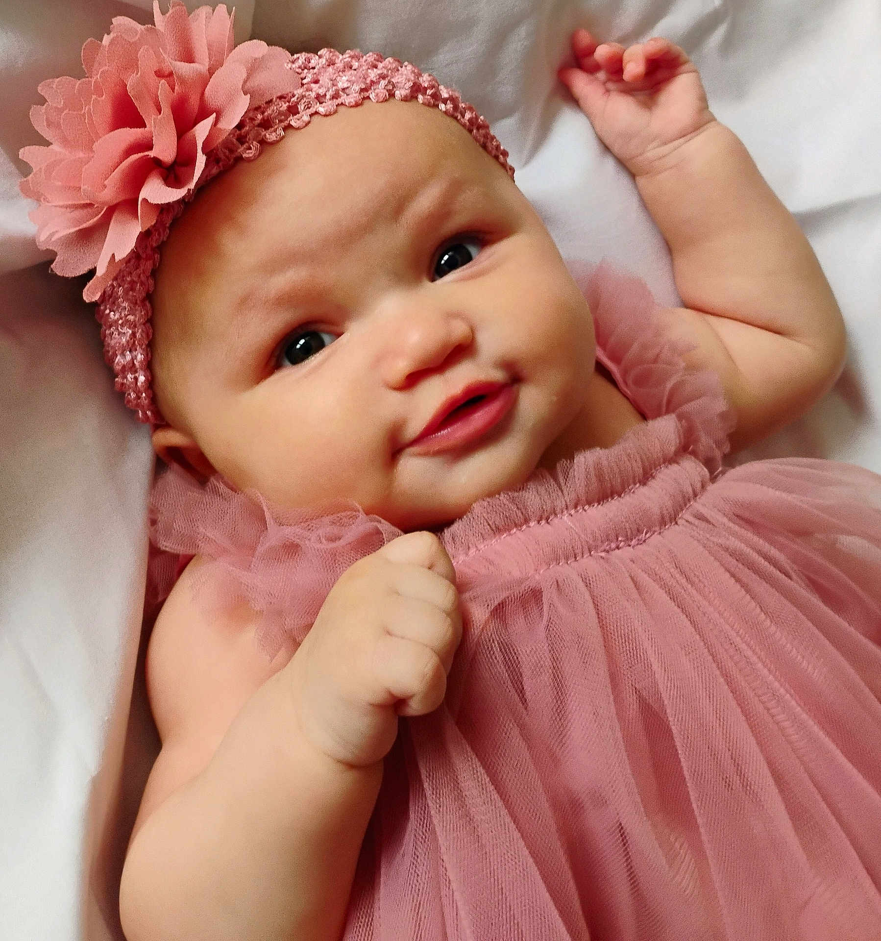Azira is registered to the contest to win money with this photo: baby, infant, pink_dress, headband, flower, cute, smile, face, skin, hand, lying_down, soft, white_background, portrait, child, adorable, close_up, young, tulle, fabric