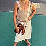 Allya a rejoint le concours — aidez-le/la à gagner de superbes lots ! child, girl, standing, fashion, pose, outdoor, sidewalk, green_pavement, white_skirt, beige_top, sandals, brown_purse, cross_necklace, hair_tied_back, casual_clothing, sunlight, street, confident, accessories, young