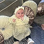 baby, child, smiling, headband, dress, polka_dot, couch, pillow, soft_furniture, indoor, footwear, sitting, cute, happy, portrait, infant, cozy, hand, face, expression