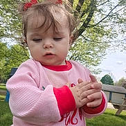 Nyx joined the competition — help win amazing prizes! toddler, child, outdoor, grass, tree, pink_sweater, red_cuffs, curly_hair, hair_bows, hands, park, daylight, person, cute, young_child, nature, picnic_table, casual_clothing, expression, curiosity