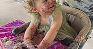 Nyx is registered to the contest to win money with this photo: toddler, child, cake, birthday_cake, purple_frosting, high_chair, outdoor, party, messy, happy, smiling, food, celebration, table, person, curly_hair, face_paint, dirt, playful, fun