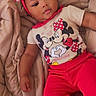 baby, child, infant, red_bow, headband, mickey_mouse, minnie_mouse, tshirt, red_pants, blanket, bed, cute, portrait, smiling, relaxed, indoors, person, clothing, baby_girl, lying_down