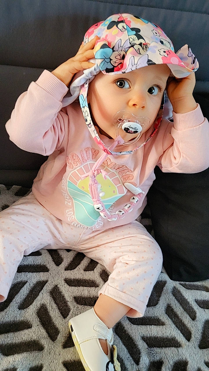 Amélia a rejoint le concours — aidez-le/la à gagner de superbes lots ! baby, baby_toddler_clothing, cap, cool, costume_hat, eyelash, fashion_accessory, fun, happy, headgear, headwear, neck, person, personal_protective_equipment, pink, sitting, sleeve, sock, surprise, t_shirt