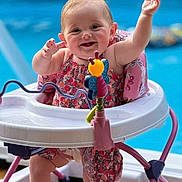 Sunnie Jae joined the competition — help win amazing prizes! baby, child, smiling, happy, baby_walker, toy, pool, outdoor, summer, romper, pink, blue, wooden_floor, playful, infant, raising_hands, cute, person, sitting, sunlight