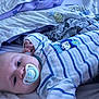 baby, pacifier, bed, blanket, pillow, onesie, striped_clothing, infant, sleepwear, cute, face, child, indoor, resting, soft_toys, comfort, lying_down, blue, textile, sleep