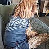 blanket, canine, casual, comfort, couch, dog, domestic_animal, fluffy_fur, fur, harley_davidson_shirt, home_interior, indoor, living_room, pet_clothing, relaxed, seated, side_view, small_dog, textile, wooden_furniture