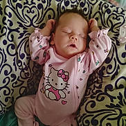 Edith is registered to the contest to win money with this photo: baby, infant, sleeping, pink_outfit, onesie, hello_kitty, cushion, patterned_fabric, portrait, indoors, sitting, arms_raised, closed_eyes, peaceful, nursery, pacifier, furniture, textile, cute, child