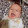 Edith is registered to the contest to win money with this photo: baby, infant, child, smiling, laughing, open_mouth, face, portrait, lying_down, indoors, cushion, blanket, patterned_fabric, onesie, clothing, brown_hair, bedroom, furniture, close_up, happy