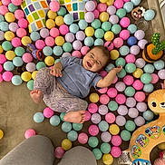 Lucia joined the competition — help win amazing prizes! baby, child, toy, plastic_ball, colorful, play, happy, smile, pillow, floor, carpet, clothing, legs, indoor, pastel_colors, cushion, cute, infant, person, playroom