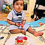 Vihaan is registered to the contest to win money with this photo: toddler, child, birthday, cake, strawberry, play_mat, bow_tie, party, indoor, floor, balloons, window, table, stroller, curious, cute, celebration, food, messy_hands, footwear_free