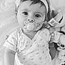 baby, baby_accessory, black_and_white, child, clothing, cute, expression, face, hand, headband, indoor, infant, lying_down, newborn, onesie, pacifier, plush_toy, portrait, sleepwear, soft_blanket