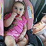 baby, infant, child, car_seat, keys, teething, pink_clothing, bow_headband, car_interior, warning_label, earrings, hand, legs, cute, portrait, seat, safety_strap, chewing, vehicle, playful