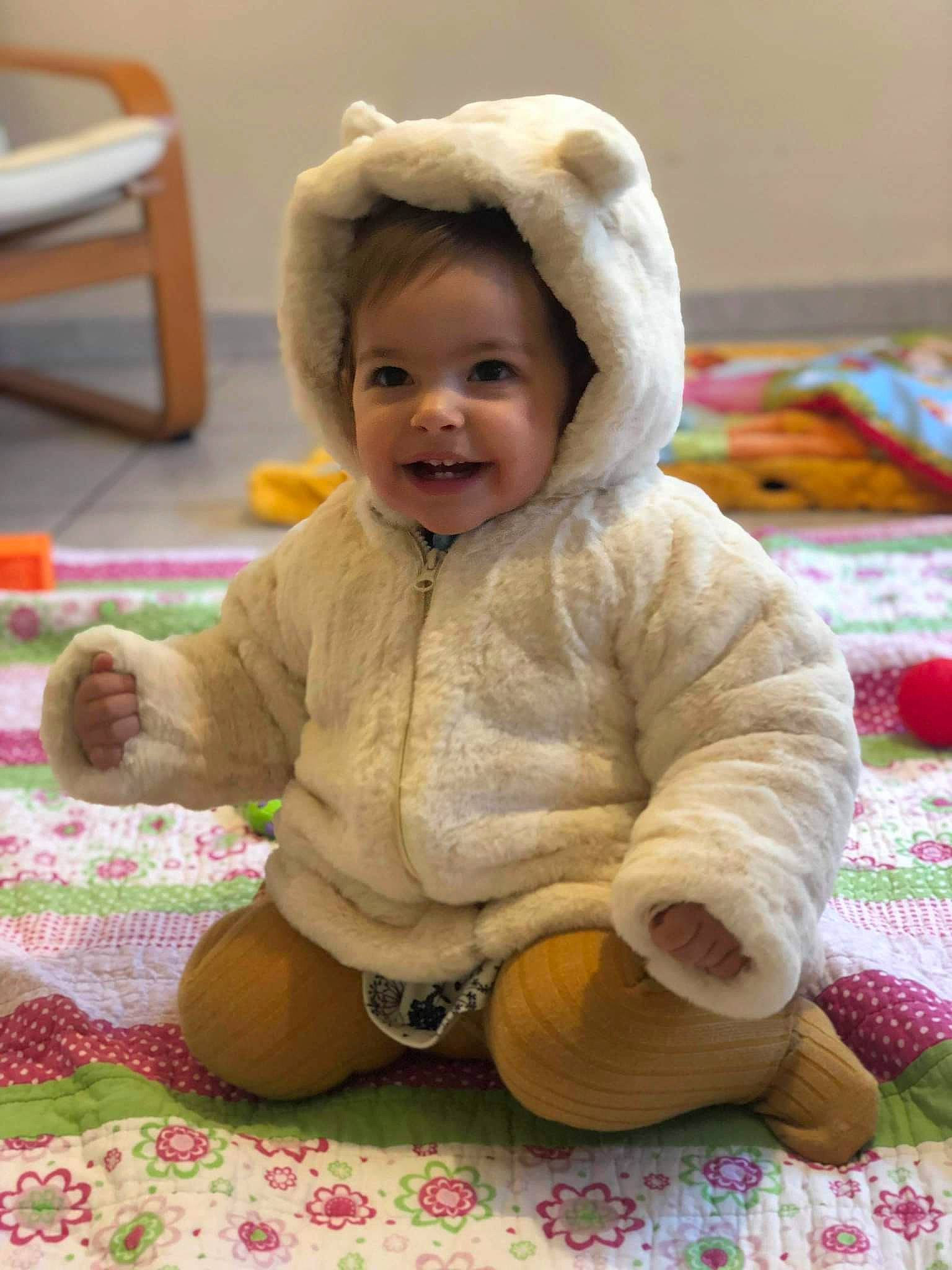 Melia participe au concours pour gagner de l'argent avec cette photo : baby, baby_toddler_clothing, cheek, child, comfort, face, flooring, fun, grass, happy, joy, outerwear, pattern, person, pink, skin, sleeve, smile, textile, toddler