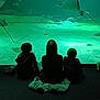 children, aquarium, stingrays, fish, underwater, silhouettes, green_light, seated, observation, marine_life, water, rocks, sand, dark, indoor, family, leisure, curiosity, back_view, nature