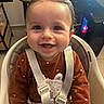 baby, smiling, high_chair, brown_outfit, safety_harness, indoor, child, happy, cute, person, seat, furniture, computer, technology, face, portrait, infant, young_child, clothing, home