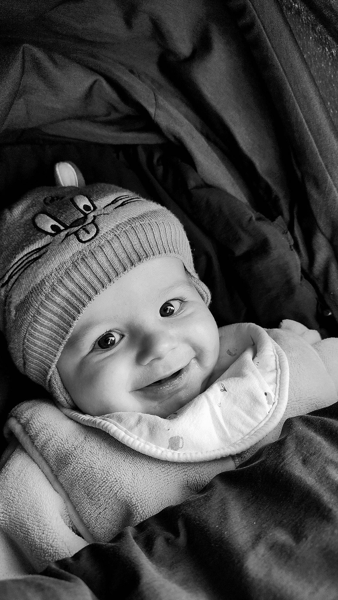Eloan participe au concours pour gagner de l'argent avec cette photo : baby, black, black_and_white, cap, cheek, child, comfort, flash_photography, grass, grey, happy, headwear, laugh, monochrome, monochrome_photography, person, sitting, sleeve, smile, style