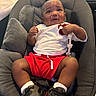 Ramari Roberson is registered to the contest to win money with this photo: baby, infant, child, sitting, cushion, chair, white_shirt, red_shorts, toy, beads, socks, sneakers, footwear, indoor, expression, curious, puzzled, skin, person, comfortable