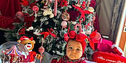 Alba participe au concours pour gagner de l'argent avec cette photo : baby, child, christmas_tree, holiday, red_clothing, headband, bow, snow_globe, teddy_bear, decorations, festive, indoor, carpet, plush, toy, seasonal, celebration, christmas, cute, portrait