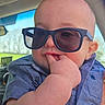 baby, child, sunglasses, blue_shirt, hand, face, car_interior, window, outdoor, cute, portrait, person, infant, casual_clothing, skin, head, eyes, fingers, summer, sunlight