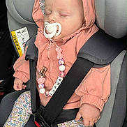 Lyana a rejoint le concours — aidez-le/la à gagner de superbes lots ! baby, beaded_chain, car_interior, car_seat, child, clip, cute, floral_leggings, headwear, hood, infant, pacifier, peaceful, person, pink_jacket, safety, seatbelt, sleeping, socks, transportation