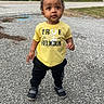 toddler, child, standing, yellow_shirt, black_pants, outdoor, pavement, suburban, house, trees, curious, person, footwear, grass, daytime, casual_clothing, sidewalk, young_child, urban, nature
