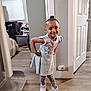 Bella is registered to the contest to win money with this photo: child, smiling, indoor, dress, boots, flooring, cartoon_print, happy, person, standing, home, room, door, window, leggings, wall, hair_bun, footwear, wood_floor, cozy