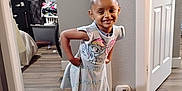 Bella joined the competition — help win amazing prizes! child, smiling, indoor, dress, boots, flooring, cartoon_print, happy, person, standing, home, room, door, window, leggings, wall, hair_bun, footwear, wood_floor, cozy