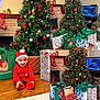 christmas_tree, baby, child, smiling, santa_hat, red_outfit, gifts, gift_bags, presents, ornaments, fireplace, stocking, living_room, hardwood_floor, fish_tank, holiday_decor, festive, cozy, portrait, holiday_scene