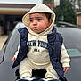 child, baby, hoodie, puffer_vest, sneakers, car, outdoor, portrait, bokeh, cheeks, expression, cute, hood, sitting, street, casual_clothing, new_york_logo, hands, eyes, winter_clothing